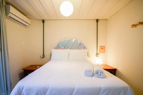 a bedroom with a white bed with two towels on it at Own Búzios Beach Hotel in Búzios