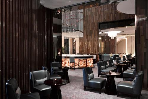a waiting room with chairs and tables and a bar at Melia Jinan in Jinan