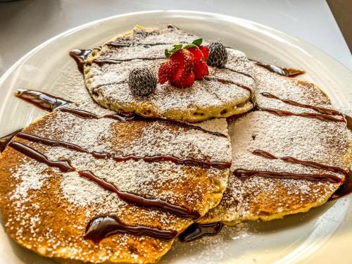 two pancakes with powdered sugar and strawberries on a plate at Tityra Lodge in Monteverde Costa Rica