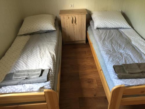 two twin beds in a room with wooden floors at Domek przy stawie in Nur
