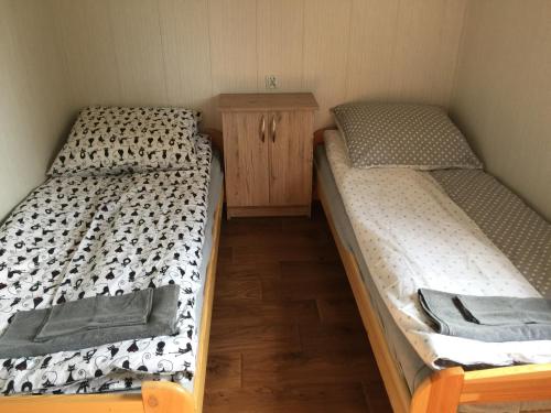 two twin beds in a room with a wooden cabinet at Domek przy stawie in Nur