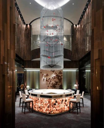a lobby with a large chandelier and a table and chairs at Melia Jinan in Jinan