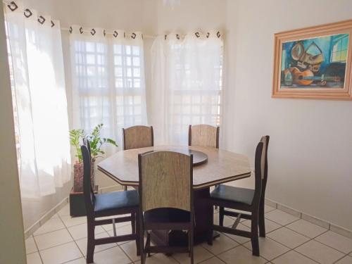 a dining room with a wooden table and chairs at Casa Azul Antares 3 Quartos - Pet Friendly in Londrina