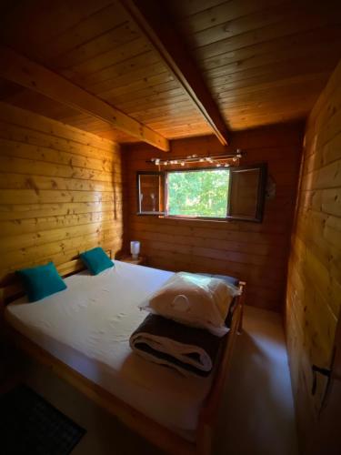 a bed in a wooden cabin with a window at Maison 2 chambres proche Dijon chalet niché dans la nature in Saint-Maurice-sur-Vingeanne