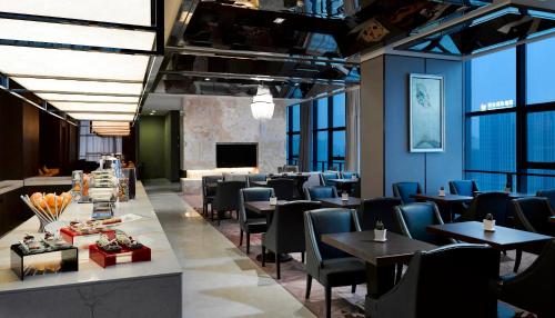 a restaurant with tables and chairs in a room with windows at Melia Jinan in Jinan