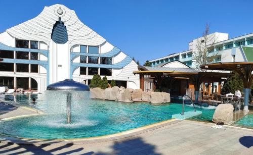 a swimming pool with a fountain in front of a building at Spa Residence Carbona Apartment 105 in Hévíz