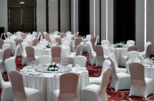 a room full of tables and chairs with white tablecloths at Melia Jinan in Jinan