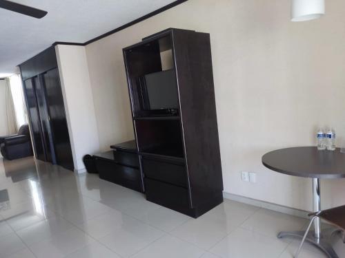 a living room with a black entertainment center with a table at Hotel Mary Celaya in Celaya