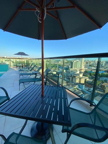 a table and chairs on a balcony with an umbrella at Logic Hotel Volta Redonda in Volta Redonda
