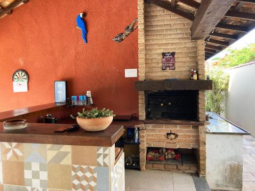 eine Außenküche mit einem Kamin und einem Vogel an der Wand in der Unterkunft Incrivel loft proximo a praia c pisc em Buzios RJ in Búzios