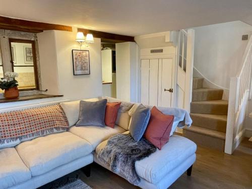 uma sala de estar com um sofá com almofadas em HEBE COTTAGE - Idyllic and homely with attention to detail em Atworth