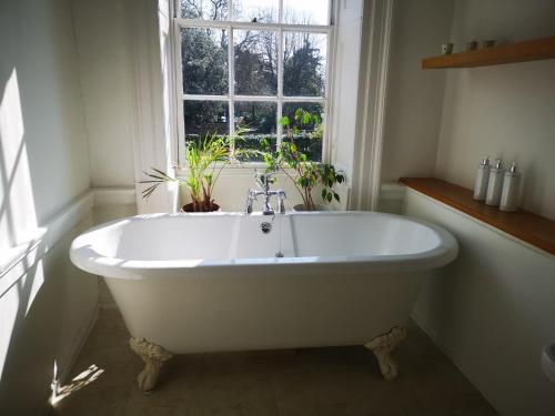 uma banheira branca na casa de banho com uma janela em East Pallant Bed and Breakfast, Chichester em Chichester