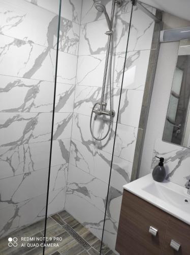 a shower in a bathroom with a marble wall at Cozy loft apartament in Sighetu Marmaţiei