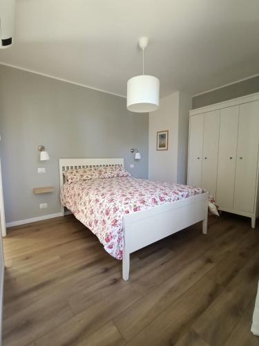 a white bedroom with a bed with a floral bedspread at RossoMattone CountryHouse in Sulmona