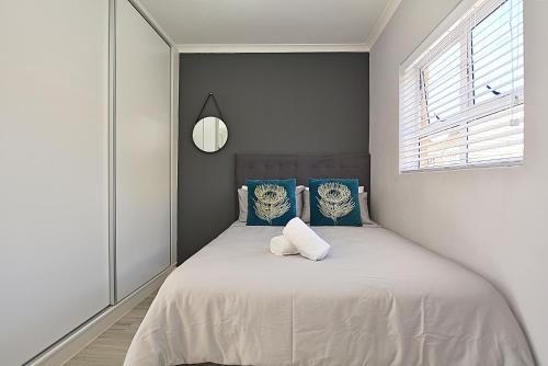 a bedroom with a bed with blue pillows and a clock at Modern Studio Apartment in Blouberg in Cape Town