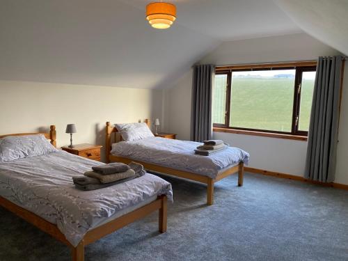 ein Schlafzimmer mit zwei Betten und einem großen Fenster in der Unterkunft Enegar Accommodation in Stromness