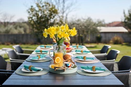 a long table with plates of food and a vase of flowers at Villa Frida in Zambratija