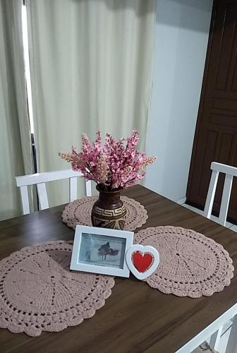a table with a picture and a vase of flowers at loft harmonia in Blumenau