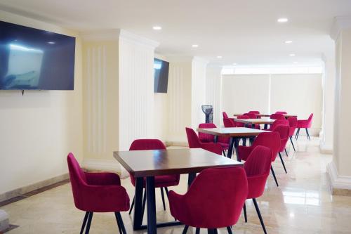 a dining room with tables and red chairs at REAL DE LA PEÑA HOTEL 2 in Querétaro