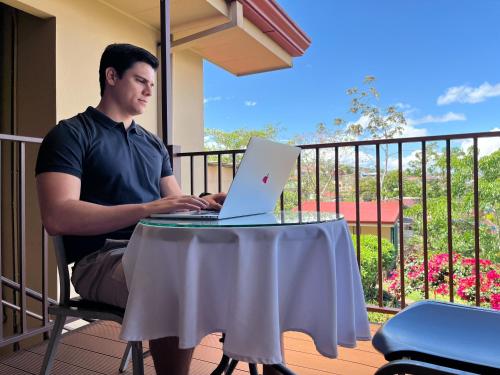 a man sitting at a table with a laptop at Legacy Boutique Hotel in Quesada