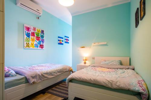 two beds in a room with blue walls at Sunset House in Vlorë
