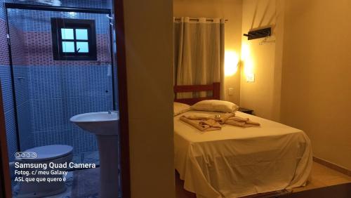 a bedroom with a bed and a bathroom with a sink at Pousada Girar do Sol in Nova Friburgo