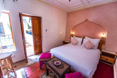 Un dormitorio con una gran cama blanca y una mesa en Riad Zahri, en Marrakech