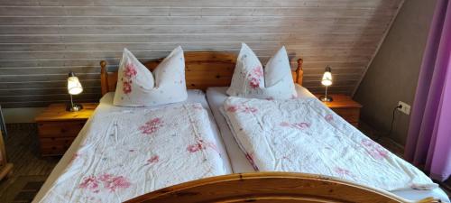 two beds with white sheets and pink flowers on them at Ferienwohnung im Rohrdachhaus in Wustrow