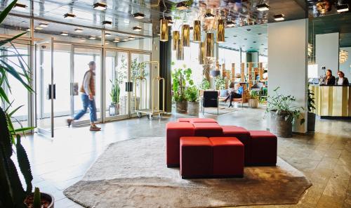 a lobby with red stools and people walking in a store at Harbour Living by Jutlandia - Hostel Style in Frederikshavn