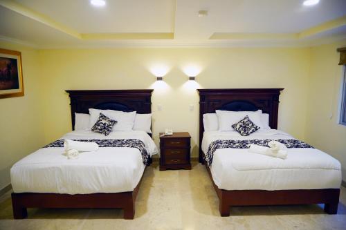 a hotel room with two beds with white pillows at REAL DE LA PEÑA HOTEL 2 in Querétaro