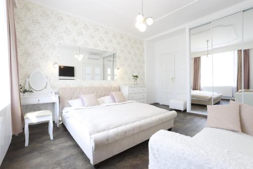 a white bedroom with two beds and a mirror at Wellness Pension Ametyst in Český Krumlov