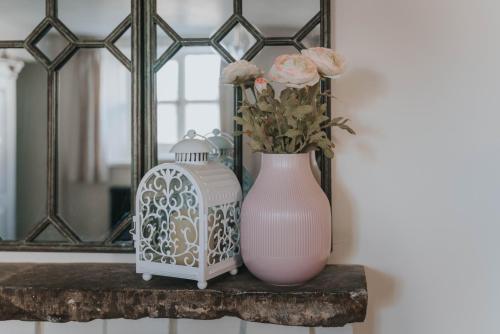 a pink vase with flowers on a table in front of a mirror at The Burrow Escape in Branston