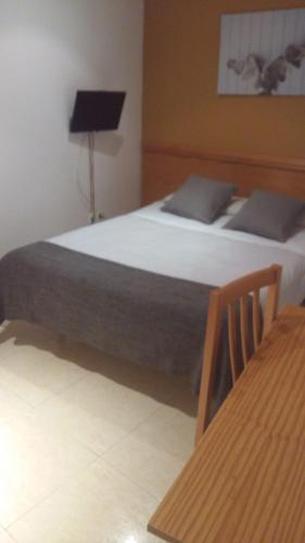 1 dormitorio con cama, lámpara y mesa en Hostal La Cañada Segoviana, en Valmojado