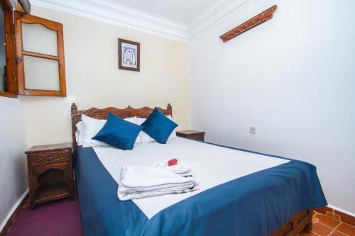 a bed with blue and white sheets and blue pillows at Hotel Al kassaba in Chefchaouene