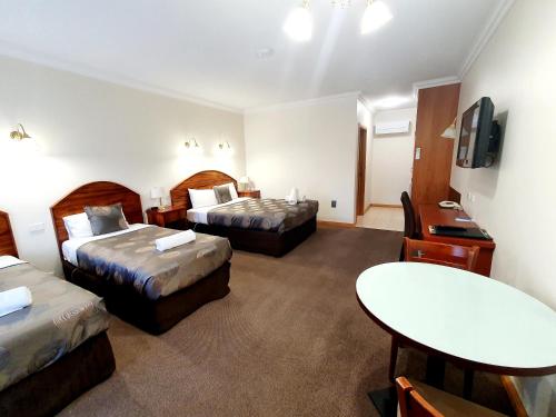 a hotel room with two beds and a table at Golden Grain Motor Inn in Horsham
