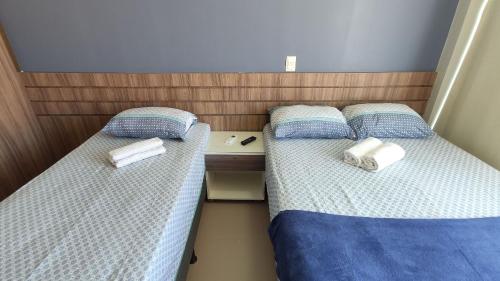 Dos camas en una habitación pequeña con toallas. en Areias do Mar | 2 Quartos Garden Familia A113, en Barra de São Miguel