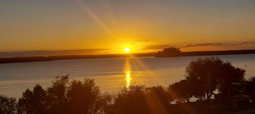 a sunset over a body of water with the sun setting at north beach depto 6 in Colón
