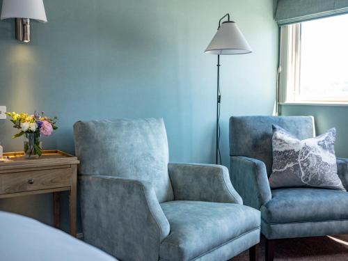 a bedroom with two chairs and a lamp and a bed at 415 Marine Parade in Napier