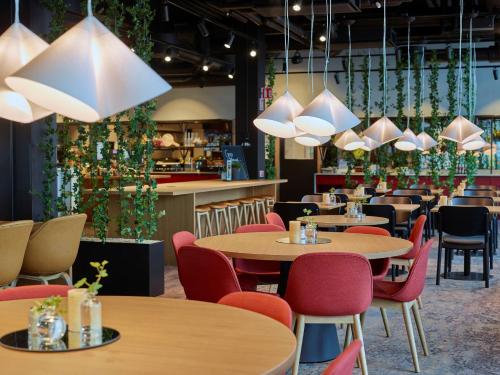 a restaurant with tables and chairs and plants at Scandic Örebro Central in Örebro