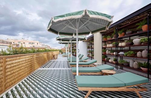 a row of lounge chairs with an umbrella on a balcony at Radisson Blu 1882 Hotel, Barcelona Sagrada Familia in Barcelona