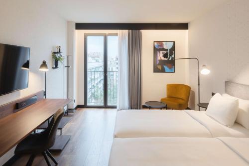 a hotel room with two beds and a desk and a television at Radisson Blu 1882 Hotel, Barcelona Sagrada Familia in Barcelona