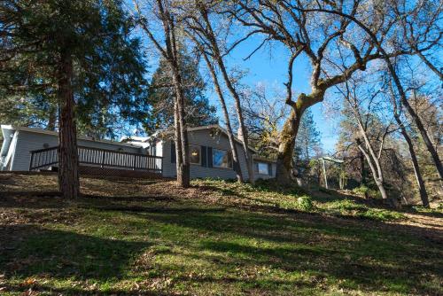 a house on a hill with trees in the foreground at Magic Escape in Oakhurst