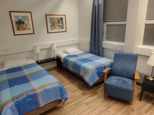 a bedroom with two beds and a blue chair at Hotel 24 - Karihaara - Kemi in Kemi