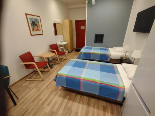 a room with two beds and chairs and a table at Hotel 24 - Karihaara - Kemi in Kemi