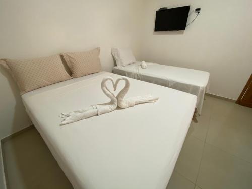 two beds in a room with a heart decoration on them at Pousada Casa da Cion in Jericoacoara