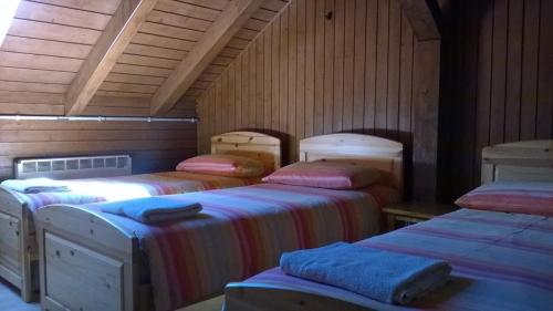 three beds in a room with wooden walls at Rifugio 2000 in Alpe Ciamporino