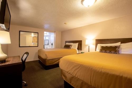 a hotel room with two beds and a desk and lamps at Celilo Inn in Williams