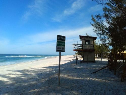 a sign on a beach with a lifeguard station at Casa temporada in Arraial do Cabo