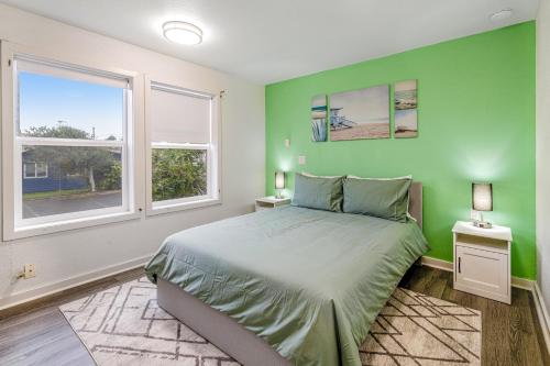 een groene slaapkamer met een bed en 2 ramen bij Coral Cove in Lincoln City
