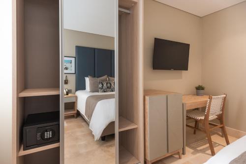 a bedroom with a bed and a desk with a television at Oz Hotel Luxury in Cartagena de Indias